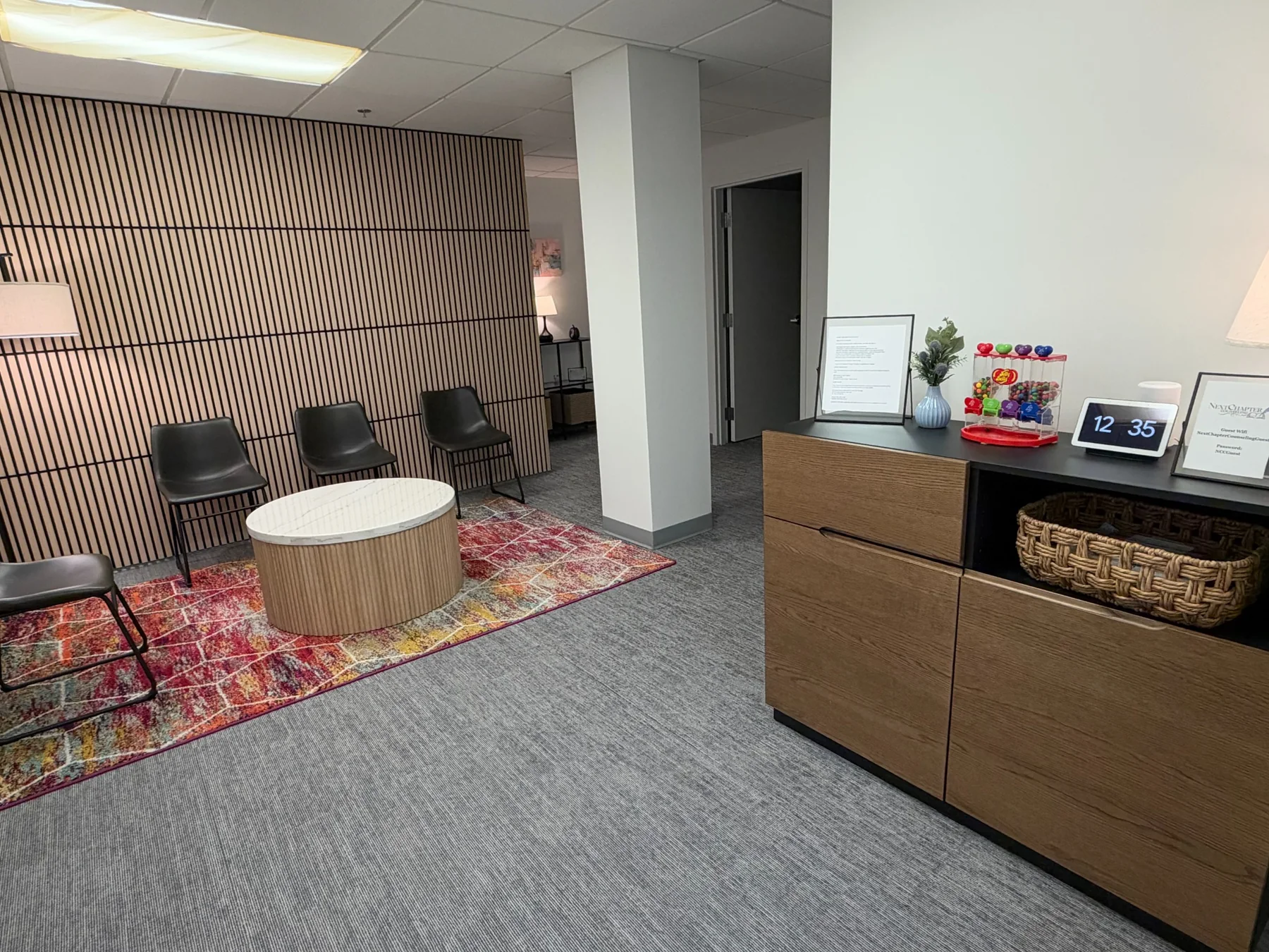 NextChapter Counseling waiting area with wood slat feature wall, black chairs, coffee table, and reception cabinet